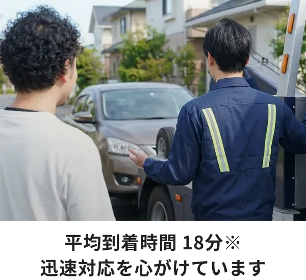 住宅街の現場に到着したロードサービスのスタッフが、利用者に対応内容を説明している様子
            