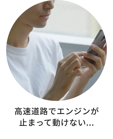 高速道路で車が動かなくなり、不安な状況でスマートフォンから助けを求めている様子。
            